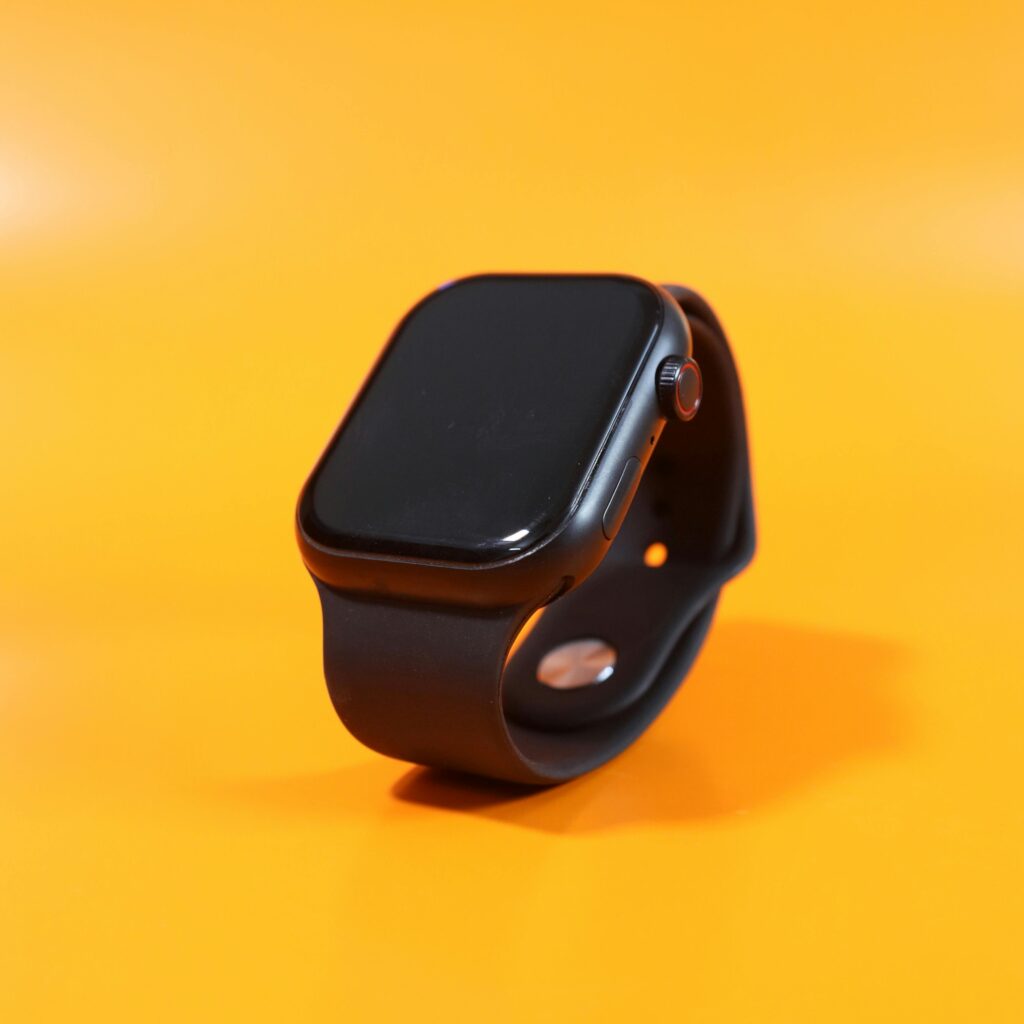 Minimalist black smartwatch with rubber strap, showcased on vivid orange background, perfect for tech enthusiasts.