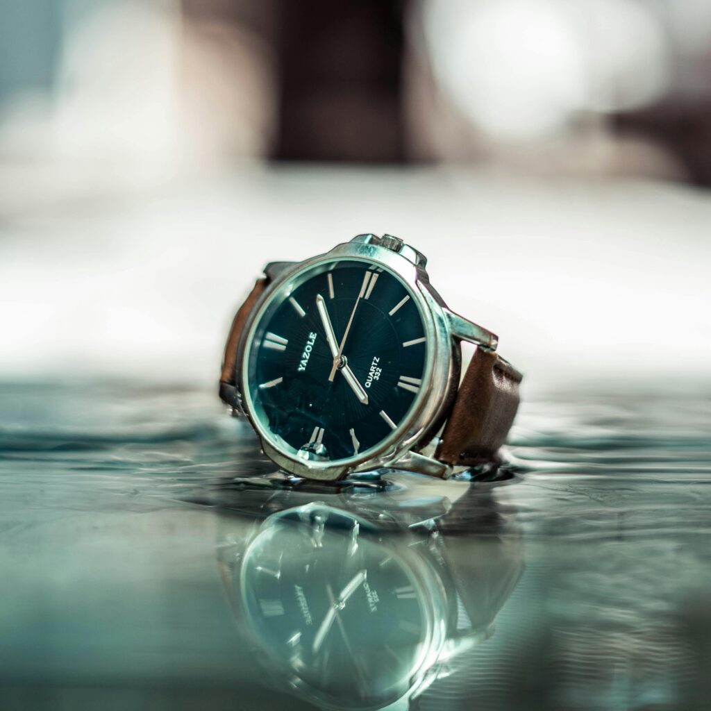Close-up of a stylish wristwatch with a blue dial on a reflective surface.
